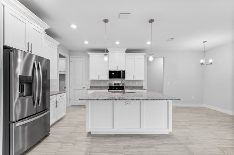 Kitchen with a white island and pendant lights inside 30340 West Bluebell Avenue, a Canary home built by Eastern Homes in Eustis, Florida